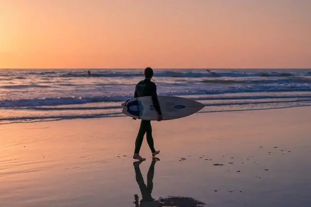 san diego surfer walking down a beach